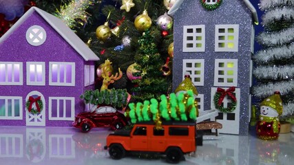 An orange car with a Christmas tree on its roof stands in the center of a Christmas town