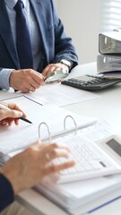 Business team analyzing financial documents, using calculators and laptop, working together on project in modern office. Audit and taxes concept