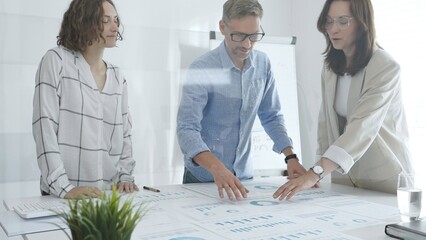 Professional colleagues reviewing financial reports, collaborating on strategic planning in contemporary workspace with collaborative atmosphere