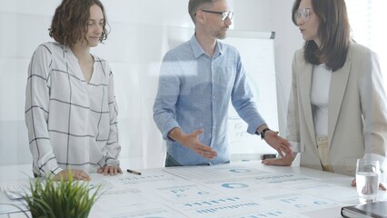 Professional colleagues reviewing financial reports, collaborating on strategic planning in contemporary workspace with collaborative atmosphere