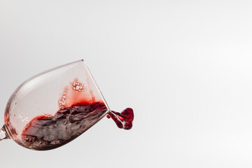 view of a tilted wine glass, the liquid is swirling inside and in motion