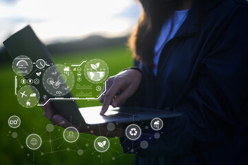 A person using a laptop in a green field, with digital icons representing technology and environmental data overlaying the scene.