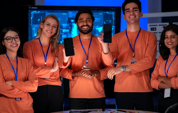 A successful team of app developers in uniform proudly presents their new software on smartphones. The blank screens are ready for a brand logo or custom user interface.