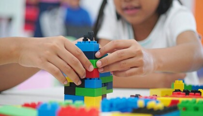 Two children's hands meticulously assemble a colorful tower of plastic building blocks, creating a vibrant scene of playful concentration.