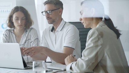 Obraz premium Business team collaborating and analyzing data on a laptop during a productive office meeting, discussing strategies and making informed decisions