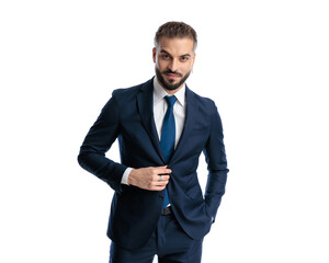 handsome mature man looking forward while adjusting navy blue suit