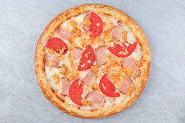 Pizza with Ham, Chicken, Fresh Tomato Slices, and Melted Cheese on Golden Crust over Gray Stone Background