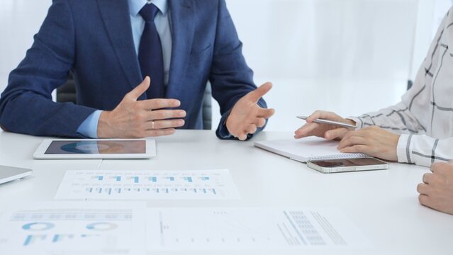 Business team engaging in a corporate meeting, discussing strategies while analyzing financial charts and graphs on a digital tablet alongside printed documents
