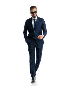 cool matue businessman with sunglasses walking with hand in pocket