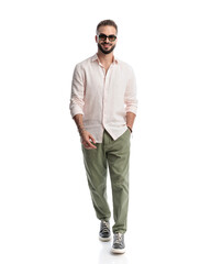 Fototapeta premium handsome casual man with sunglasses walking with hand in pocket