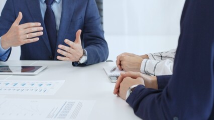 Business professionals discussing financial charts on tablet, collaborating closely while reviewing project data in modern corporate workspace