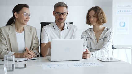 Professional team analyzing data on laptop, sharing insights during collaborative office meeting, highlighting workplace synergy and strategic planning. Business people concept