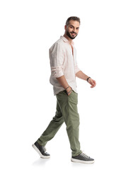 Naklejka premium happy young man walking with hand in pocket and smiling