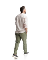 Fototapeta premium back view of casual young man walking with hands in pockets