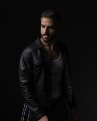 dramatic cool guy in black leather jacket looking away and posing