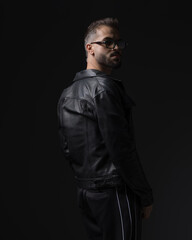 Obraz premium back view of cool young man with sunglasses looking behind and posing