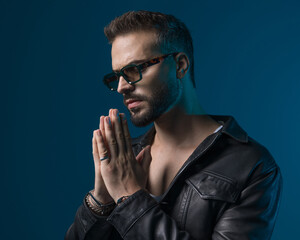 sexy bearded man with sunglasses looking to side and praying