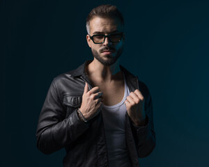 dramatic cool guy with sunglasses looking forward and adjusting jacket