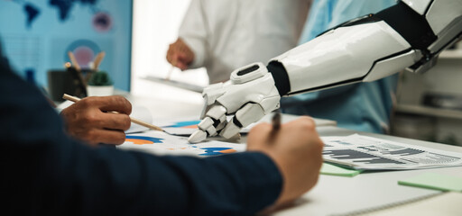 Human and robot collaborate in a modern office setting, focusing on data analysis and innovation. A dynamic interaction highlights technology integration in teamwork.Noogenesis