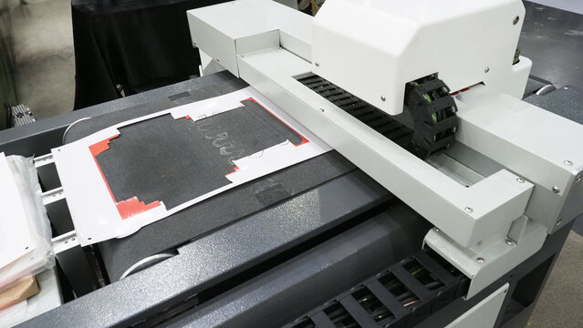 An industrial flatbed cutting and printing machine in operation.