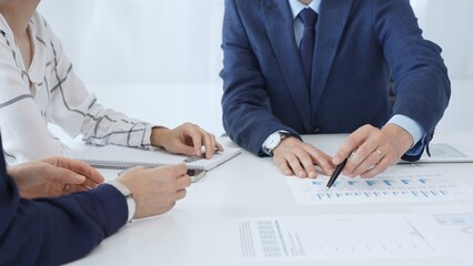 Business people engaging in a corporate meeting, discussing strategies while analyzing financial charts and graphs on a digital tablet alongside printed documents in office