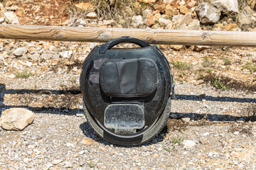 Electric unicycle leaning against wooden fence