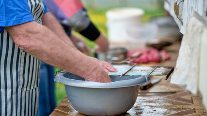 A man washes a dirty grill grate in a basin