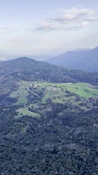 Panoramic view taken from Mirador del Far, near the medieval village of Rupit. A landscape of mountains, hills, and valleys covered in forests, with green areas illuminated by the sunset light. Spain