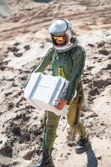 Female astronaut carrying white box in desert © karrastock