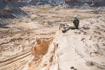 Female astronaut sitting on desert cliff © karrastock