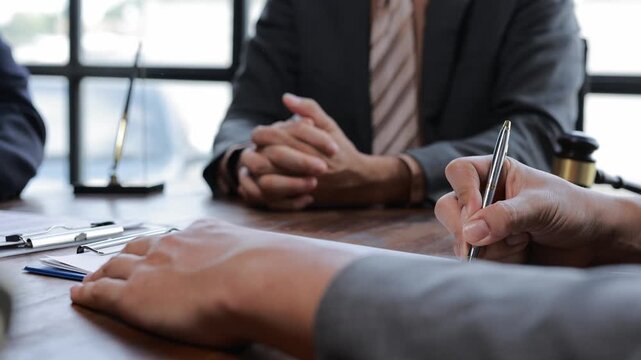 Professional business partners discussing legal agreement, carefully reviewing contract details during collaborative meeting with attorney in modern office setting