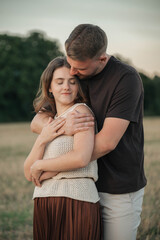Romantic couple embracing in a cornfield, standing forehead to forehead with eyes closed, expressing love, tenderness, and connection in a natural outdoor setting.
