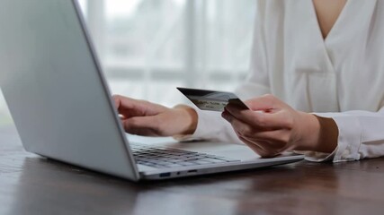 Professional woman securely processing online payment, typing credit card details on laptop keyboard while working at home office desk, focusing on digital transaction process - Powered by Adobe