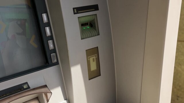Human hand interacting with ATM machine outdoors, illustrating finance, banking, cash withdrawal, payment operations and modern electronic money access in everyday life