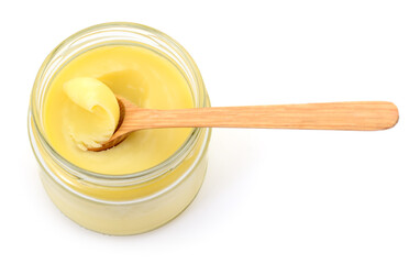 Glass jar of ghee clarified butter with wooden spoon top view
