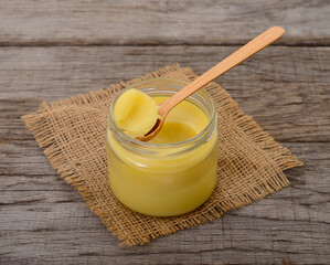 Glass jar of ghee clarified butter with wooden spoon