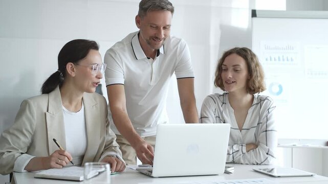 Business team collaborating and analyzing data on a laptop during a dynamic office meeting, uniting efforts to reach shared objectives and drive successful outcomes together