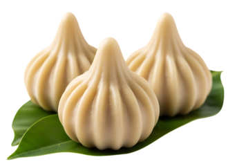 Three sweet indian modak dumplings made of rice flour and jaggery on green leaves isolated on transparent background