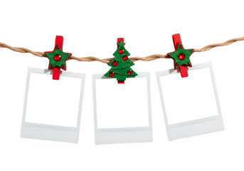 Three blank white instant photo prints hanging on a string with festive christmas clothespins isolated on transparent background