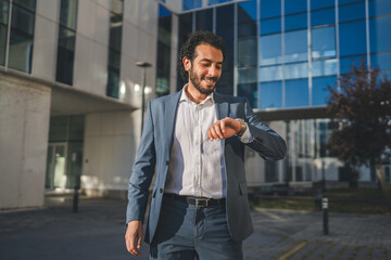 Businessman checking time on wristwatch outside office building
