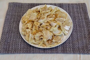 chips of gadus macrocephalus cod fillet, salted and dried, on a round white plate
