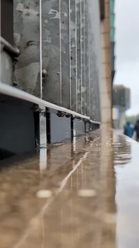 Slow motion rainwater dripping from above hitting a concrete ledge and splashing back up into the air.
