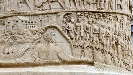 Rome, Italy - 11 January 2025. Trajan’s Column relief shows soldiers preparing to cross a river by boat, guided by a river deity and framed by fortifications and supplies.