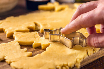 Male hands preparing festive Christmas cookies on wooden table
