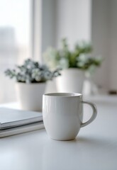 Fototapeta premium White ceramic coffee mug resting on a clean desk with blurred green plants and books in the background creating a calm and cozy workspace atmosphere