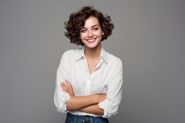 Fototapeta premium Young cheerful woman with curly hair smiling and looking confident in casual white shirt.