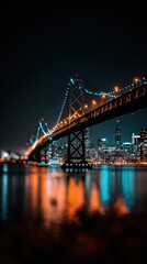 Naklejka premium A magnificent suspension bridge spans the night city, illuminated with vibrant teal and warm amber lights reflecting on the dark water below.