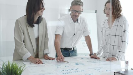 Professional team analyzing financial charts, colleagues reviewing data with focused expressions in modern workplace setting. Business people concept - Powered by Adobe