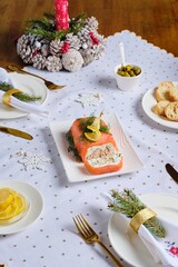 A cold appetizer, a terrine of salted salmon and smoked mackerel with cheese cream and dill, served on a white rectangular plate on a set table.