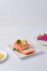 A cold appetizer, a terrine of salted salmon and smoked mackerel with cheese cream and dill, served on a white rectangular plate against a white background.